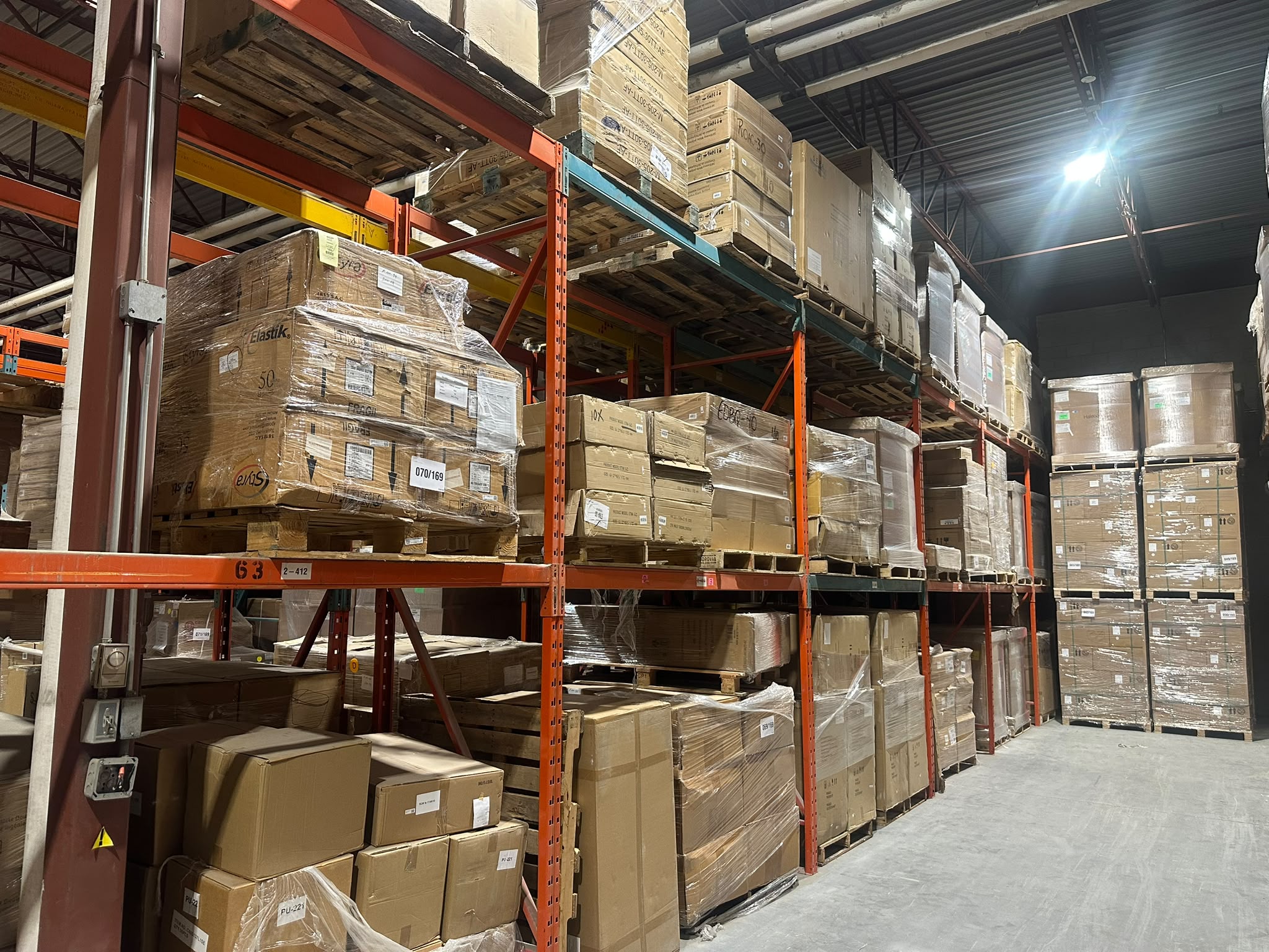 Pallet racking in GTC Logistics' Saint-Laurent warehouse, with shrink-wrapped pallets stored on orange steel shelving